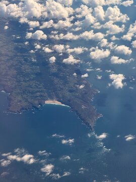 Aerial views form a plane looking through the clouds onto dramatic coastline. 