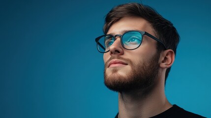 Obraz premium A young man gazing upwards, showcasing determination and focus against a blue background.