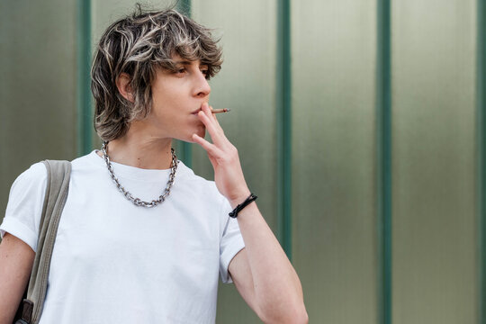Young person smoking a cigarette outdoors, taking a break - Powered by Adobe
