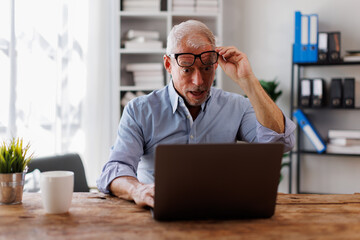 Surprised happy american Mature man holding phone looking at cellphone read good news in sms sit...