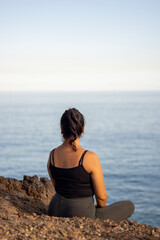 Chica mirando horizonte desde acantilado sobre el mar