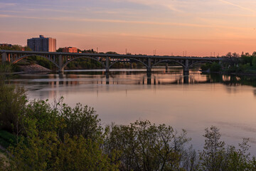 Obraz premium A bridge spans a river with a beautiful sunset in the background
