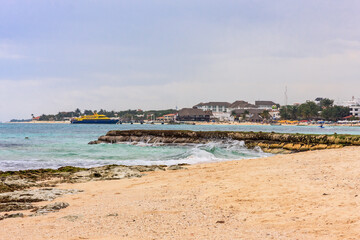 A beach with a boat in the water and a few people on the beach