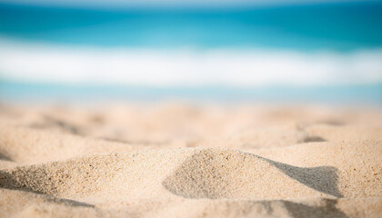 Close-up view on sand, blurred blue sea on backdrop. Summer time.