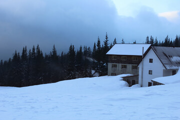 House in the winter forest, Carpathian mountains. Snowy rural landscape. Farm house in gloomy winter landscape. Snowy background, overcast. House in the mountains, Drahobrat, Ukraine