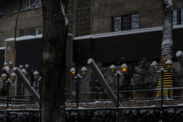 glowing street lights but above a dark building in the snowfall