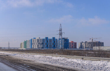 Obraz premium colored buildings of the new residential district under construction in the winter field and power lines