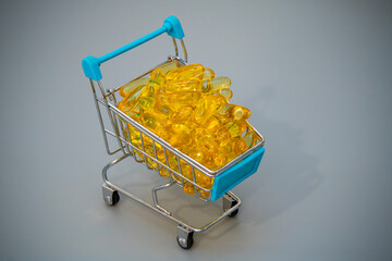 Shopping cart filled with golden capsules on a grey background