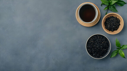 Dark tea leaves and brewed tea on grey surface.  Relaxing drink background for menu or blog