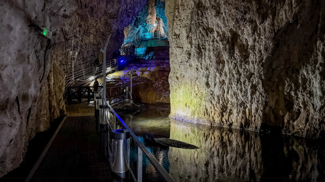 Dimly lit underground cave with a tranquil water pool and rugged rock formations, representing exploration and natural beauty  stopica pecina