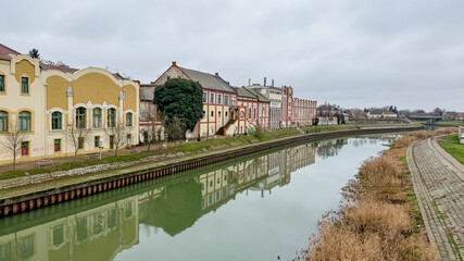 Fototapeta premium Historic European riverside architecture reflecting in a calm canal symbolizes tranquility amidst urban life, perfect for travel-related content