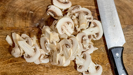 Freshly sliced mushrooms on a wooden board with a sharp knife, perfect for vegetarian cooking and meal prep