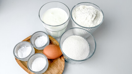 Assorted baking ingredients including flour, sugar, and an egg arranged on a table, perfect for holiday baking recipes