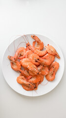 A white plate filled with cooked shrimp represents fresh seafood cuisine, ideal for summer barbecues or coastal holiday feasts
