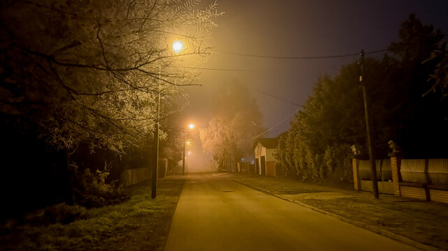 A misty, dimly lit street at night evokes mystery and solitude, ideal for Halloween or suspenseful themes