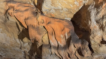 Intricate rock formations resembling flowing drapery inside a cave capture the natural beauty and mystery of geological wonders