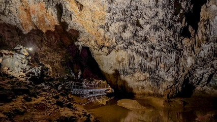 A lone explorer with a flashlight navigates a rocky, water-filled cave, highlighting adventure and exploration concepts