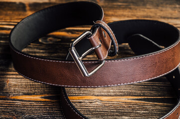 High-quality brown leather belt with silver buckle, meticulously stitched. Perfect for fashion, western, or men's accessories. Stylish and durable, showcased on a rustic wooden background.