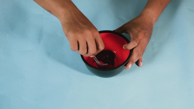 Preparing food. Close-up view showing a man hands stirring spices in a plastic bowl.