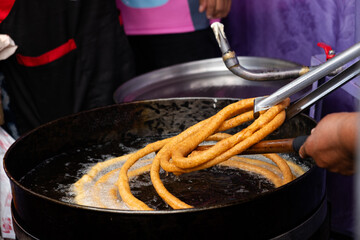 preparation of churros fried in oil in the streets of the city of la paz bolivia - street food concept