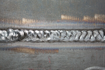 Close-up of a butt weld joint connecting two steel plates. The weld bead has a distinct rippled...