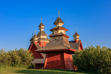 A red building with three domes and a cross on top