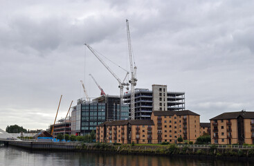 View of Riverside Apartments and  Buildings under Construction Reflected in Water on Cloudy Day 