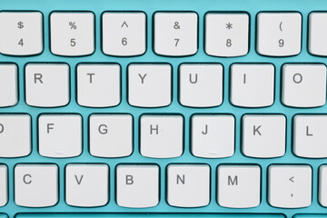 Closeup of white keyboard keys on a turquoise background