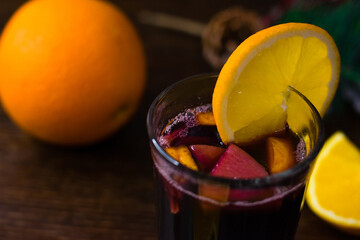 Delicious mulled wine with orange, cinnamon and honey in a glass on a dark background. Concept of a...