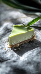 A slice of pandan cheesecake sits on rustic stone, highlighting its smooth texture and buttery crust, with fresh pandan leaves nearby.