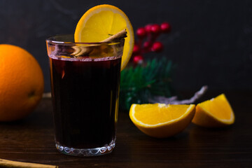 Delicious mulled wine with orange, cinnamon and honey in a glass on a dark background. Concept of a cozy winter evening, Christmas and New Year celebration