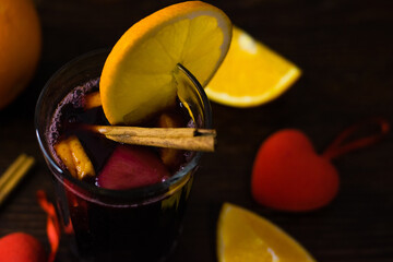 Delicious mulled wine with orange, cinnamon and honey in a glass and decorative red hearts on a...