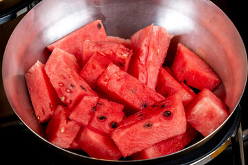 Red ripe watermelon pieces in steel bowl in top view