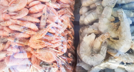 Two large plastic bags of frozen raw and cooked shrimp, on the counter of the fish market