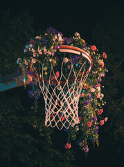 A basketball hoop made of fresh flowers stands on a basketball court, set against the night sky.