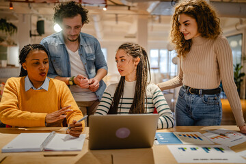 male and female colleagues research together on laptop in the office