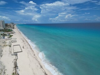 Aerial Top view of a transparent blue sea with beautiful waves at sunny day in summer. Tropical landscape from the air of ocean with azure water, sandy bottom at sunset. Cancun, Mexico.