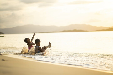 Captured in a moment, two kids frolic at the beach, embodying the essence of childhood joy and...