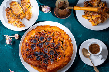 Traditional homemade banana caramel pie. French Tarte Tatin on a white plate with Turkish coffee on a green, emerald background.Top view