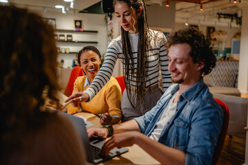 male and female colleagues research together on laptop in the office