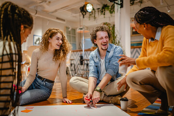 multicultural colleagues gather around a large paper on a wooden floor