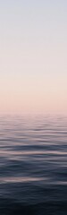 Calm ocean horizon under a pastel sunset with a serene blank sky for reflection and tranquility