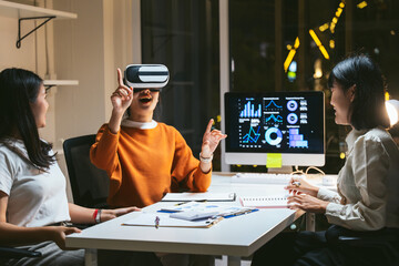 Asian businesswomen using vr headset for analyzing and visualizing financial data in office at night