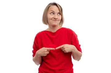 A woman in a red shirt smiling and pointing at herself against a white background.