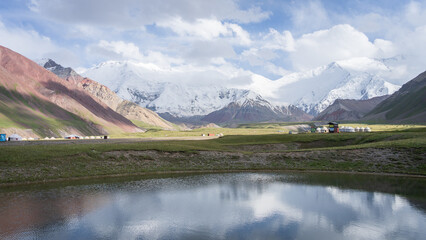 Beautiful alpine landscape with snowy Pamir Mountains and nomadic yurts and lake, Kyrgyzstan