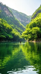 Fototapeta premium Lone Adventurer Canoeing Through Tranquil Emerald Waters Surrounded By Lush Green Mountains