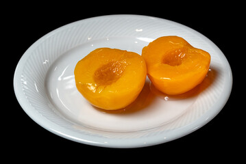 Pitted peaches in syrup in white dish isolated on black with clipping path included