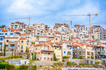 Obraz premium Construction site on the sea coast: view of tower cranes standing over tourist complex in Lustica bay, Montenegro.