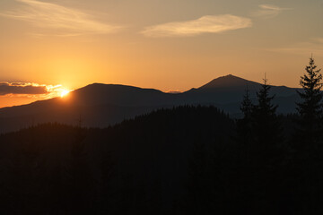 Sunset casts warm hues over mountains and forests in tranquil evening landscape. Hiking in Carpathian Mountains, Ukraine