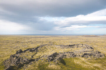 Fototapeta premium Rugged terrain of the Snafellsnes Peninsula in Iceland, featuring volcanic rock formations, open plains, and a dramatic sky stretching toward the horizon